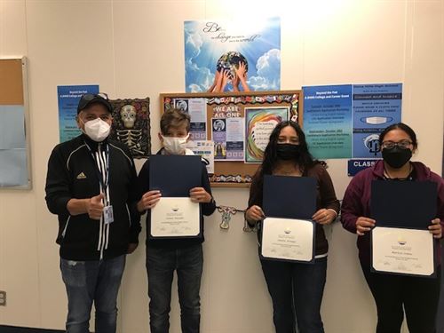 students wearing face masks and holding certificates